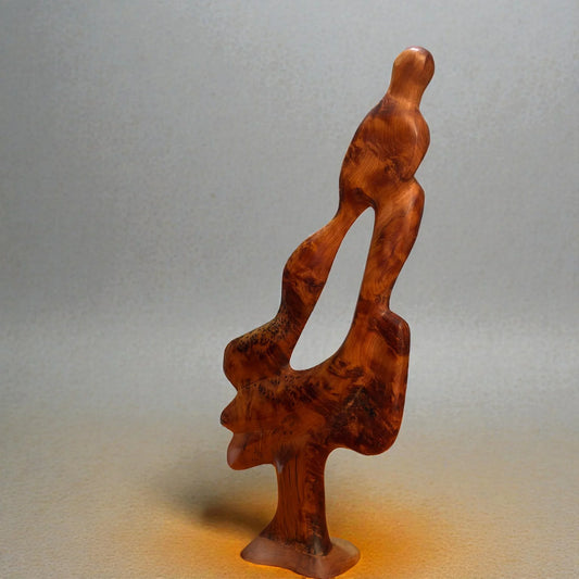 Hand-carved abstract Thuya wood sculpture displayed on a white pedestal, showing rich natural grain and polished finish