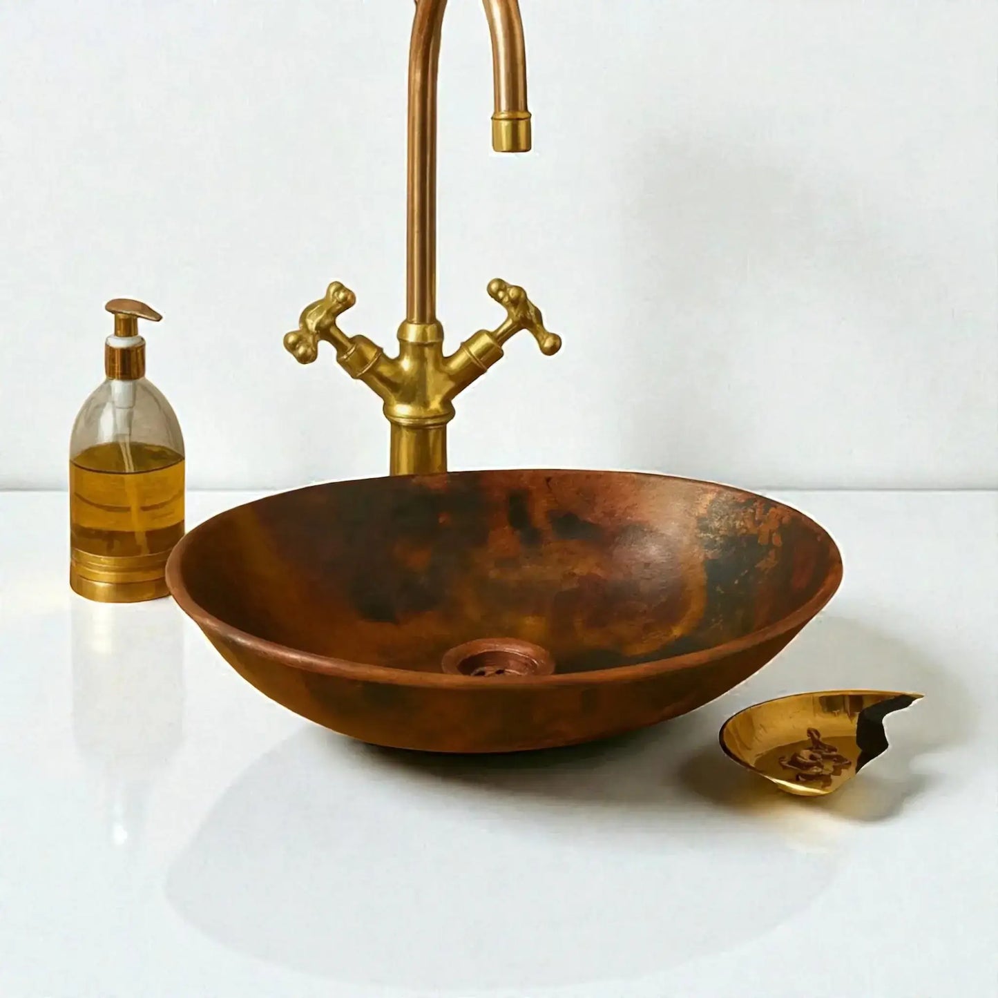 Copper sink with gold faucet and soap dispenser on a white background