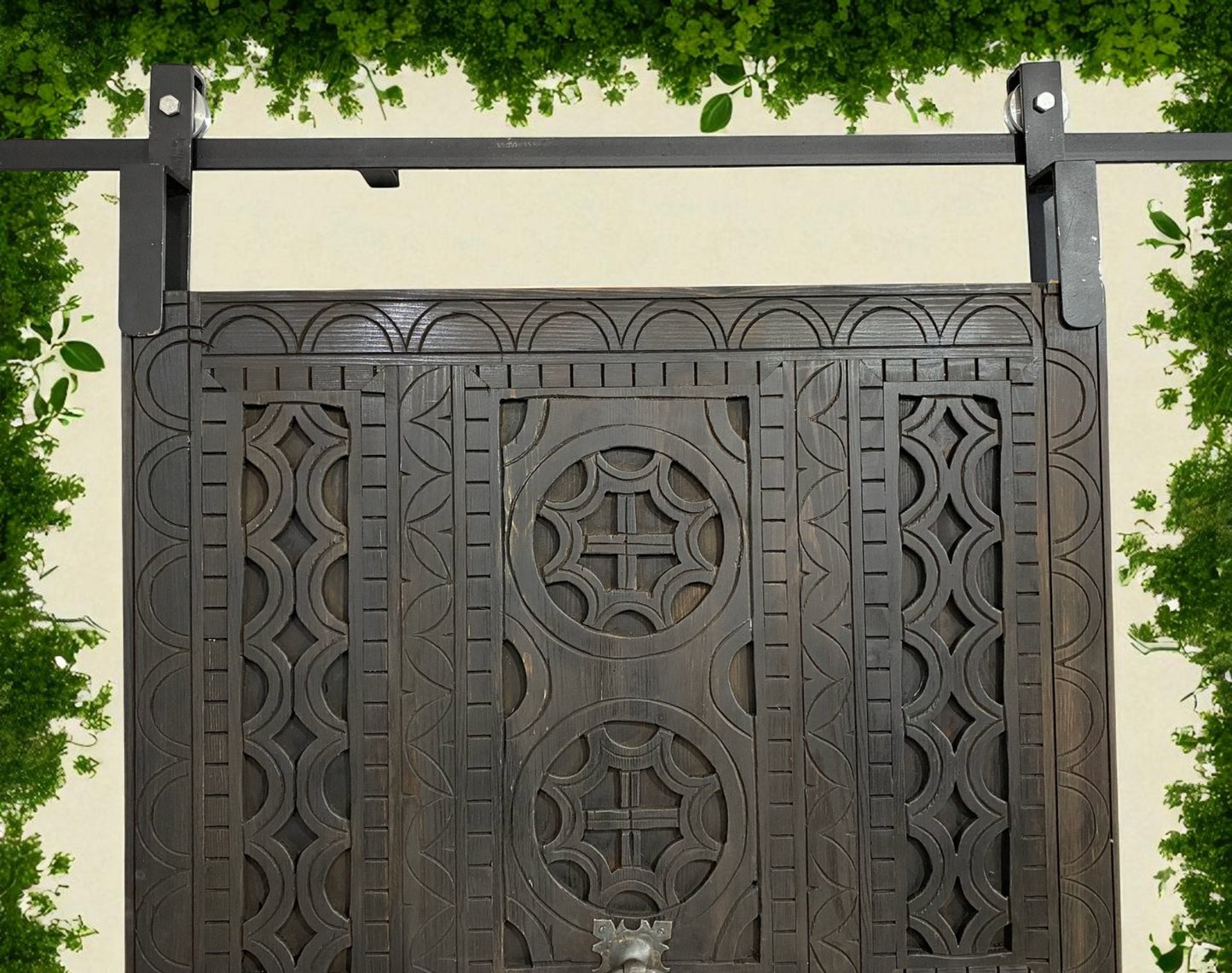Elaborately carved, dark wood barn door with iron sliding track and hardware.
