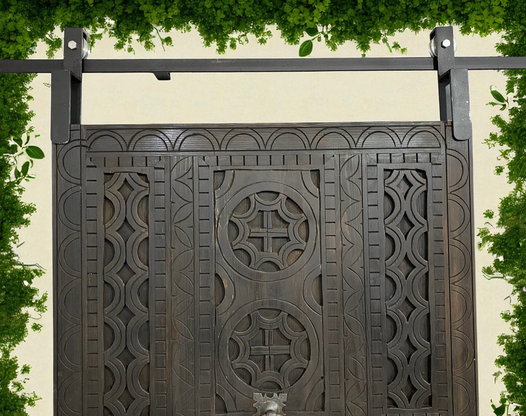 Elaborately carved, dark wood barn door with iron sliding track and hardware.
