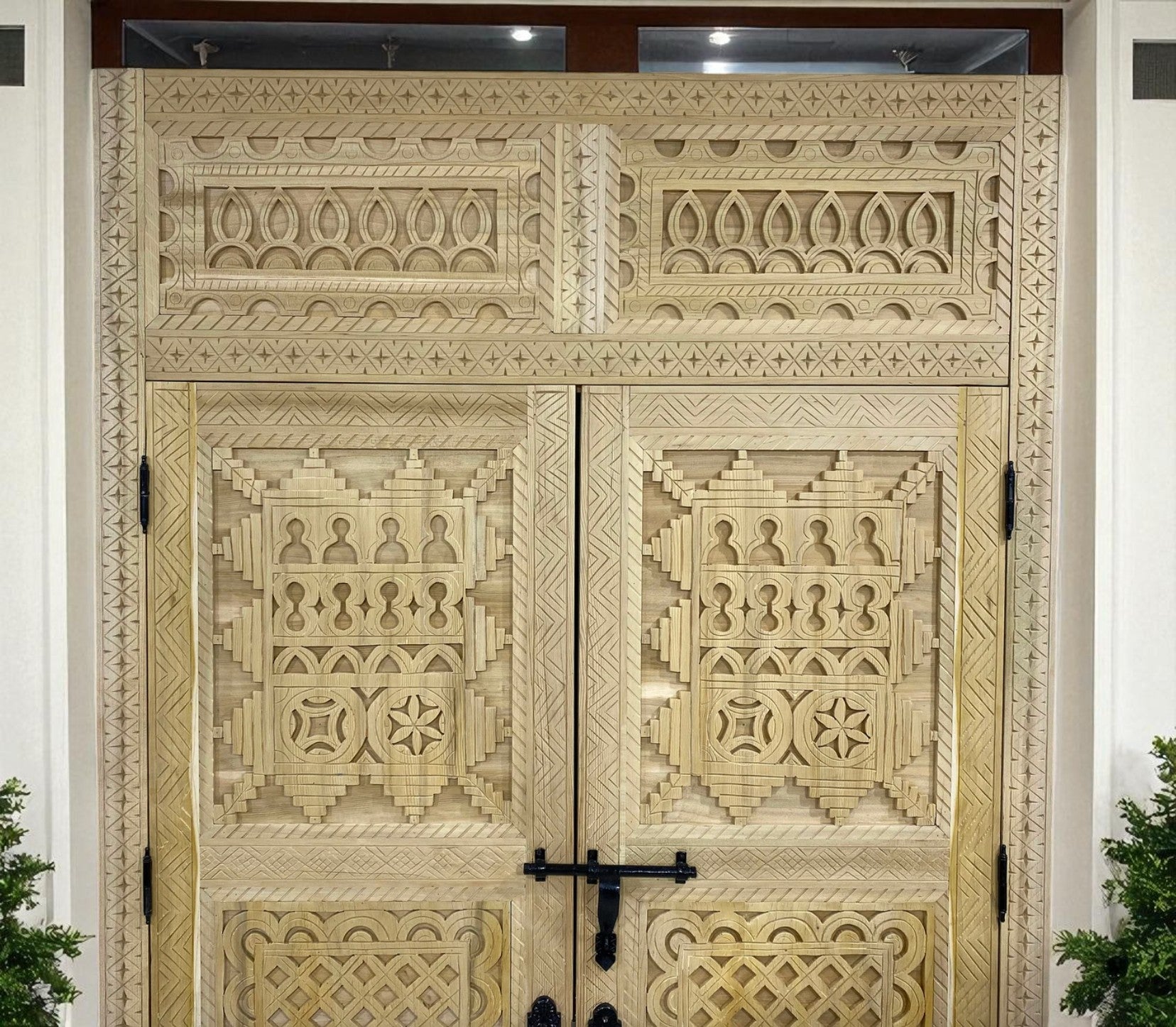 Intricately carved wooden double doors with geometric and floral patterns.