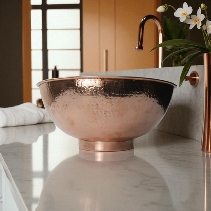 Copper vessel sink with hammered texture on marble countertop in bathroom.