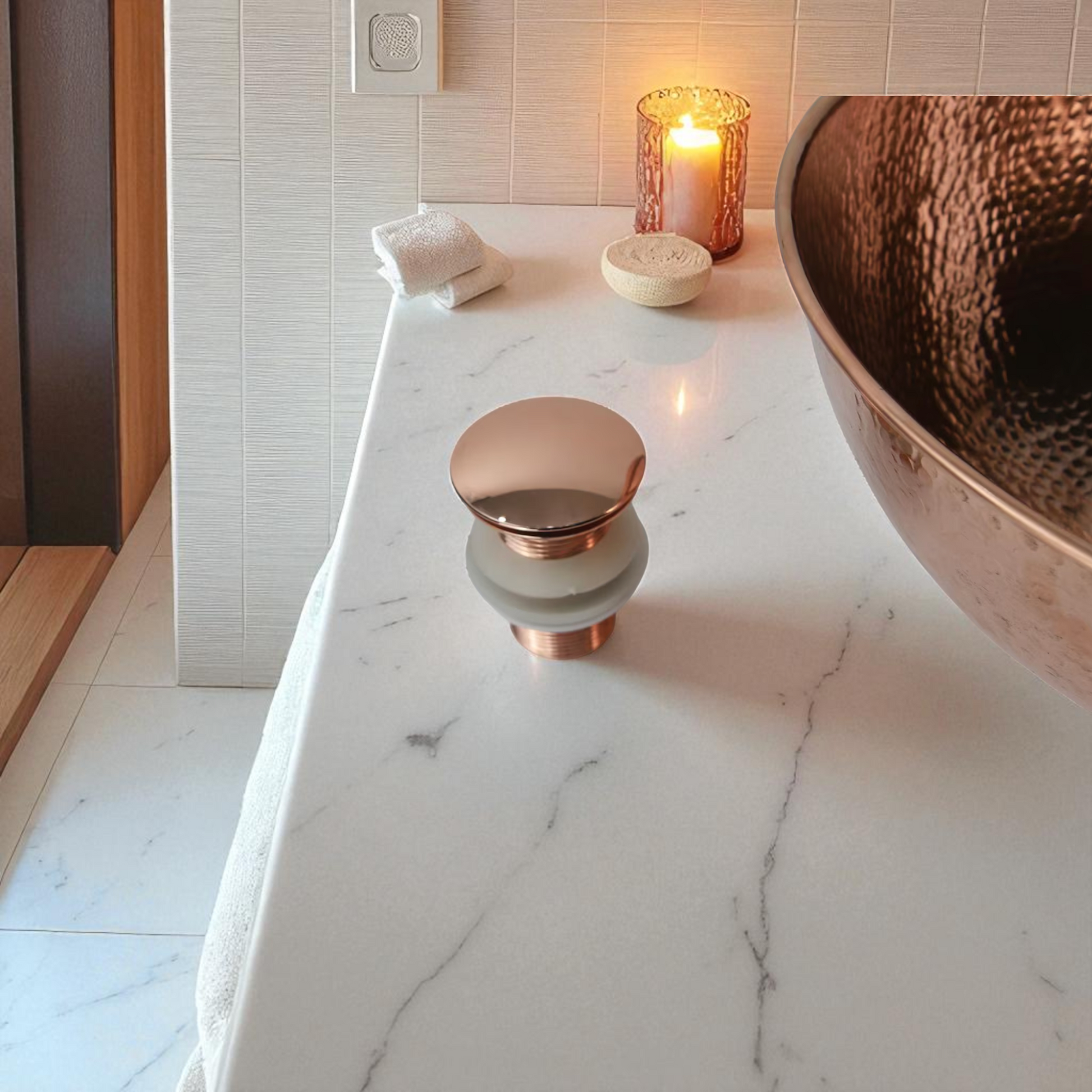 Marble countertop with copper sink, faucet, candle, and stacked towels.
