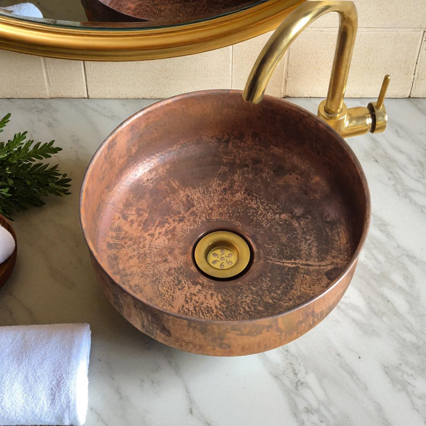 Copper vessel sink with brass faucet on a marble countertop.