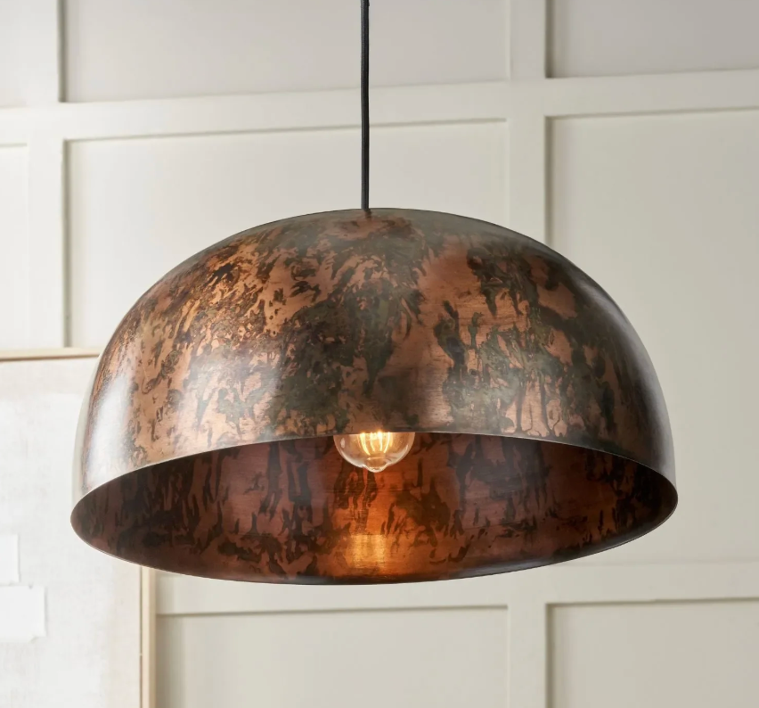 Bronze pendant light hanging against a white paneled wall