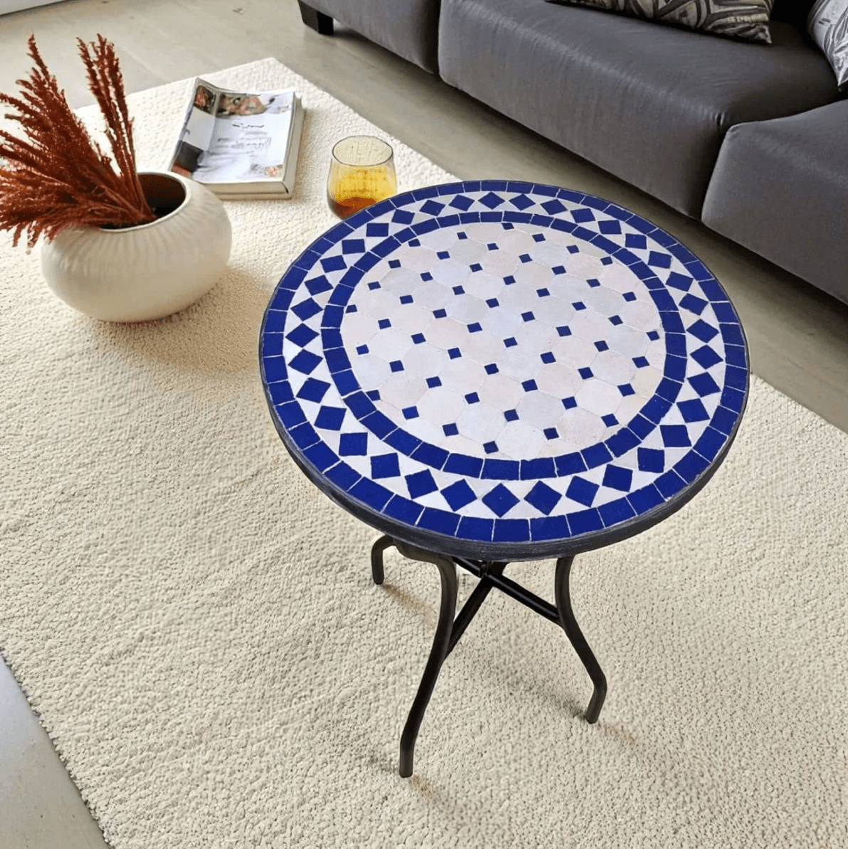 Round mosaic table with blue and white pattern in a living room setting