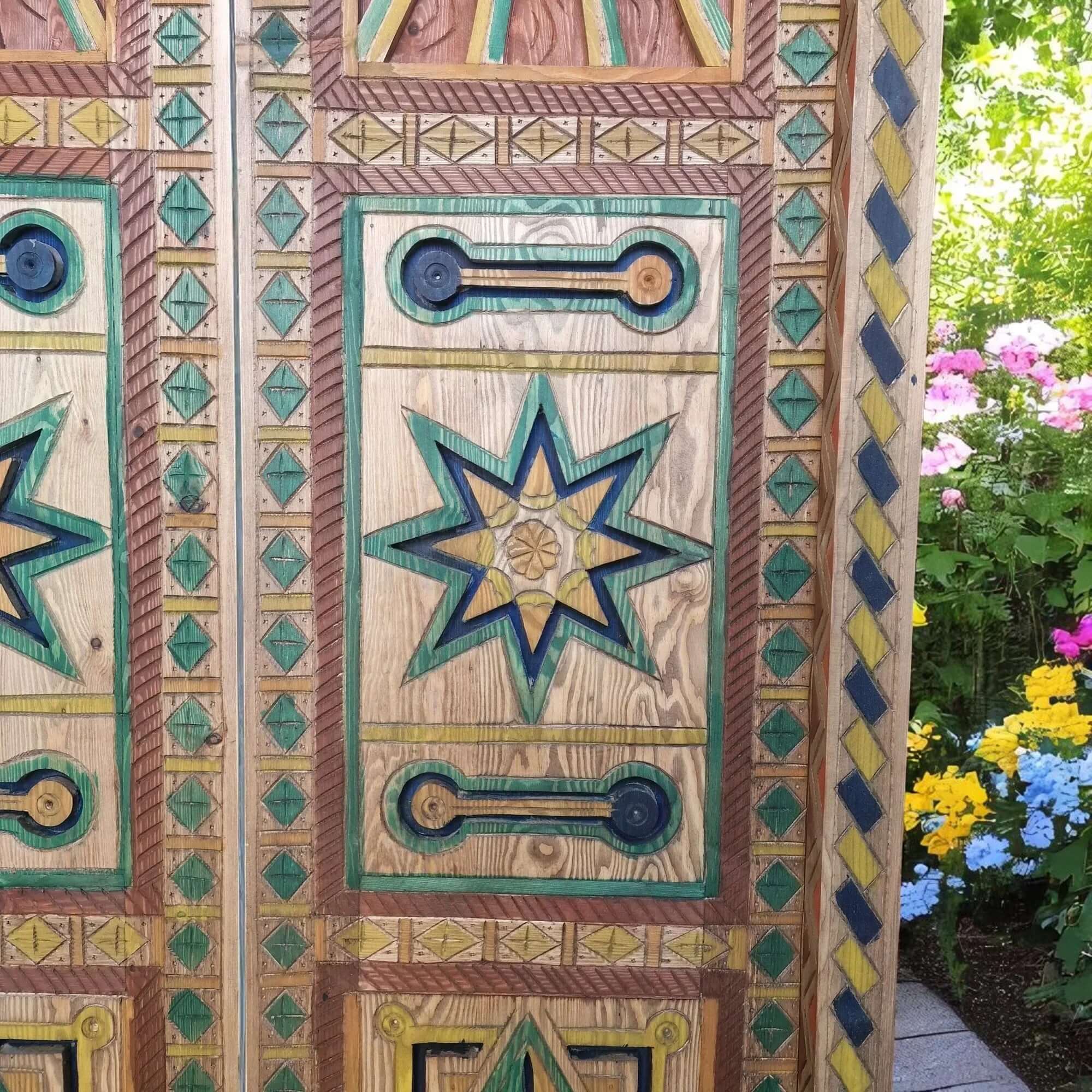 Hand-painted multicolor wooden door with geometric carving underneath