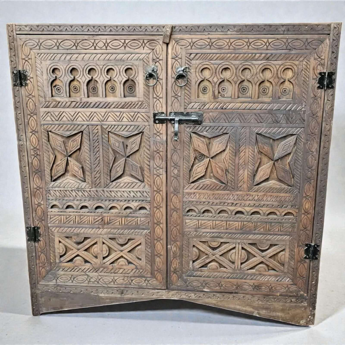 AtlasMuseCrafts handcrafted wooden cabinet with intricate Berber carvings and rustic boho style. Features double doors with metal latch and ring pulls.