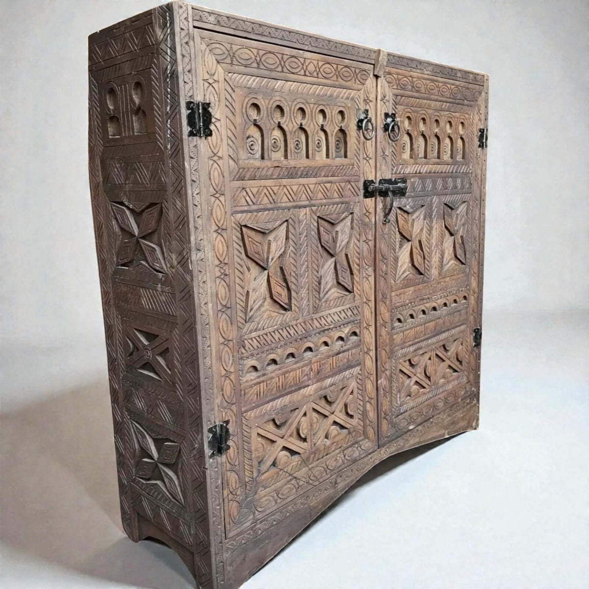 AtlasMuseCrafts handcrafted wooden cabinet with intricate Berber carvings, rustic boho style, and metal hardware. Features two doors and detailed side panels.