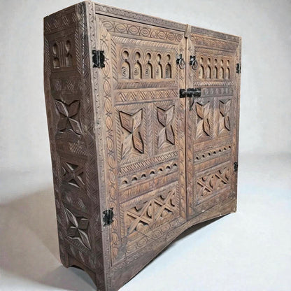 AtlasMuseCrafts handcrafted wooden cabinet with intricate Berber carvings, rustic boho style, and metal hardware. Features two doors and detailed side panels.