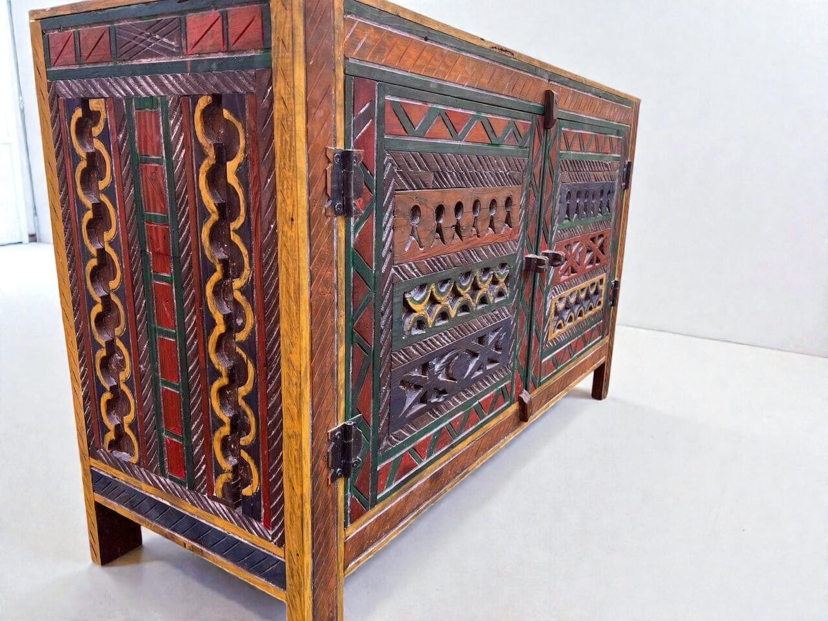 AtlasMuseCrafts handmade wooden cabinet with intricate Berber carvings in red, green, and yellow. Rustic boho style storage.