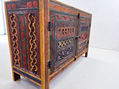 AtlasMuseCrafts handmade wooden cabinet with intricate Berber carvings in red, green, and yellow. Rustic boho style storage.