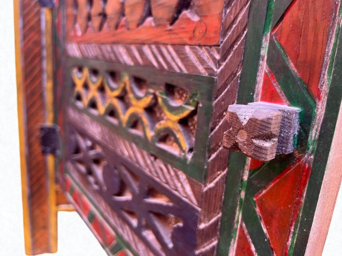 AtlasMuseCrafts handmade wooden cabinet with intricate Berber carvings, red, green, and yellow accents, and a rustic boho style.