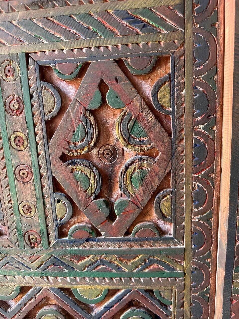 AtlasMuseCrafts handmade wooden door with brass knobs, featuring intricate hand-carved Moroccan geometric patterns in red, green, and natural wood tones.
