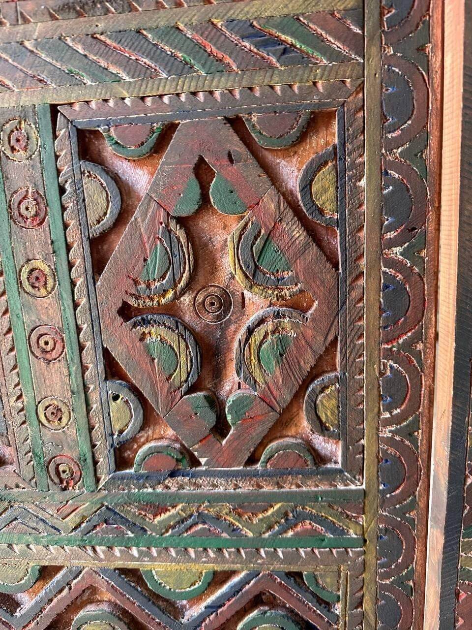 AtlasMuseCrafts handmade wooden door with brass knobs, featuring intricate hand-carved Moroccan geometric patterns in red, green, and natural wood tones.