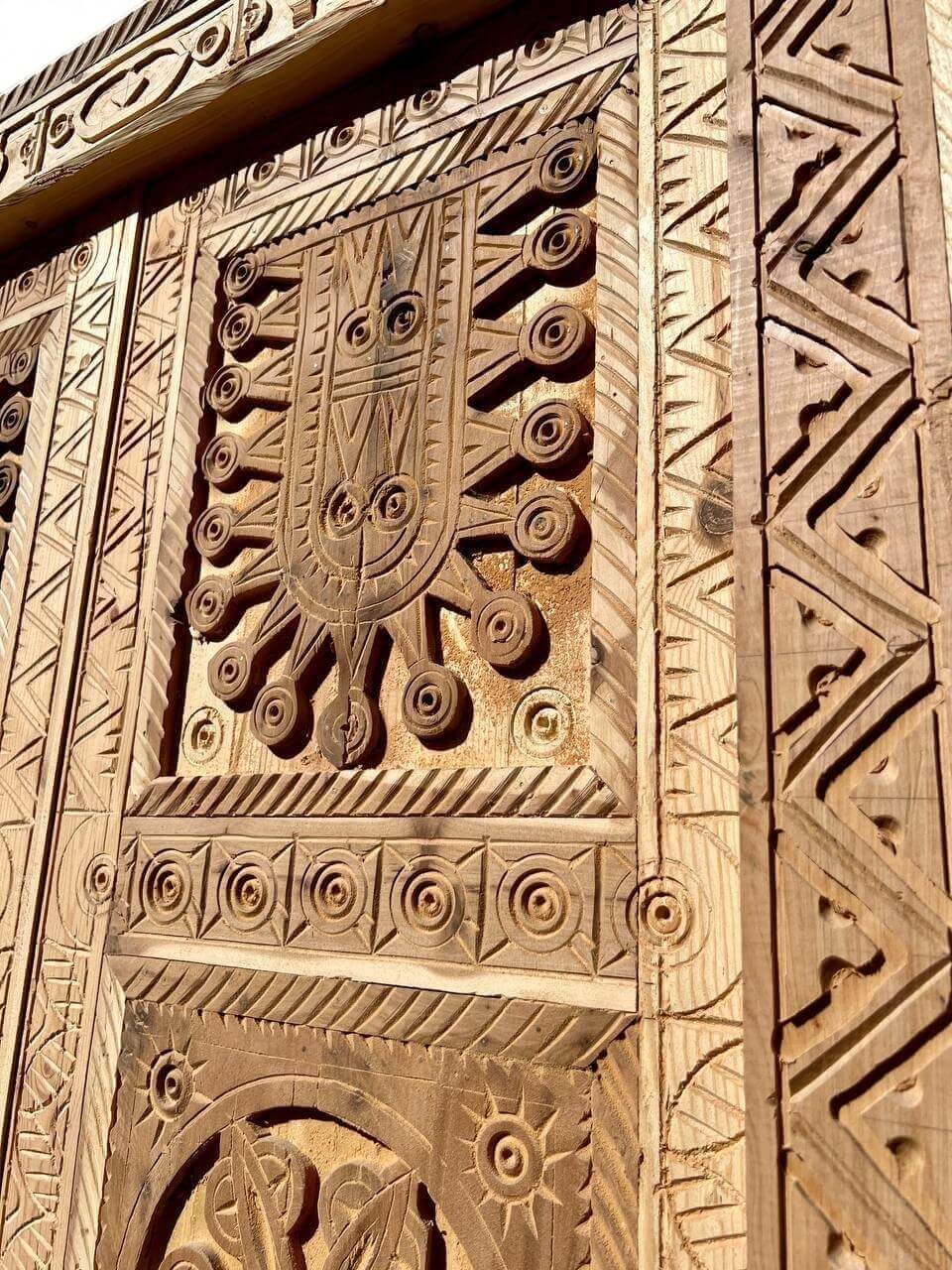 AtlasMuseCrafts antique Moroccan double door with intricate hand-carved natural wood panels featuring geometric and arabesque patterns.