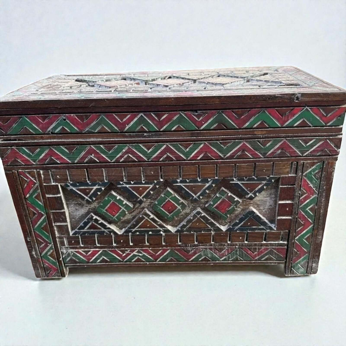 AtlasMuseCrafts custom Moroccan wood cabinet with hand-carved Berber patterns in red, green, and white.