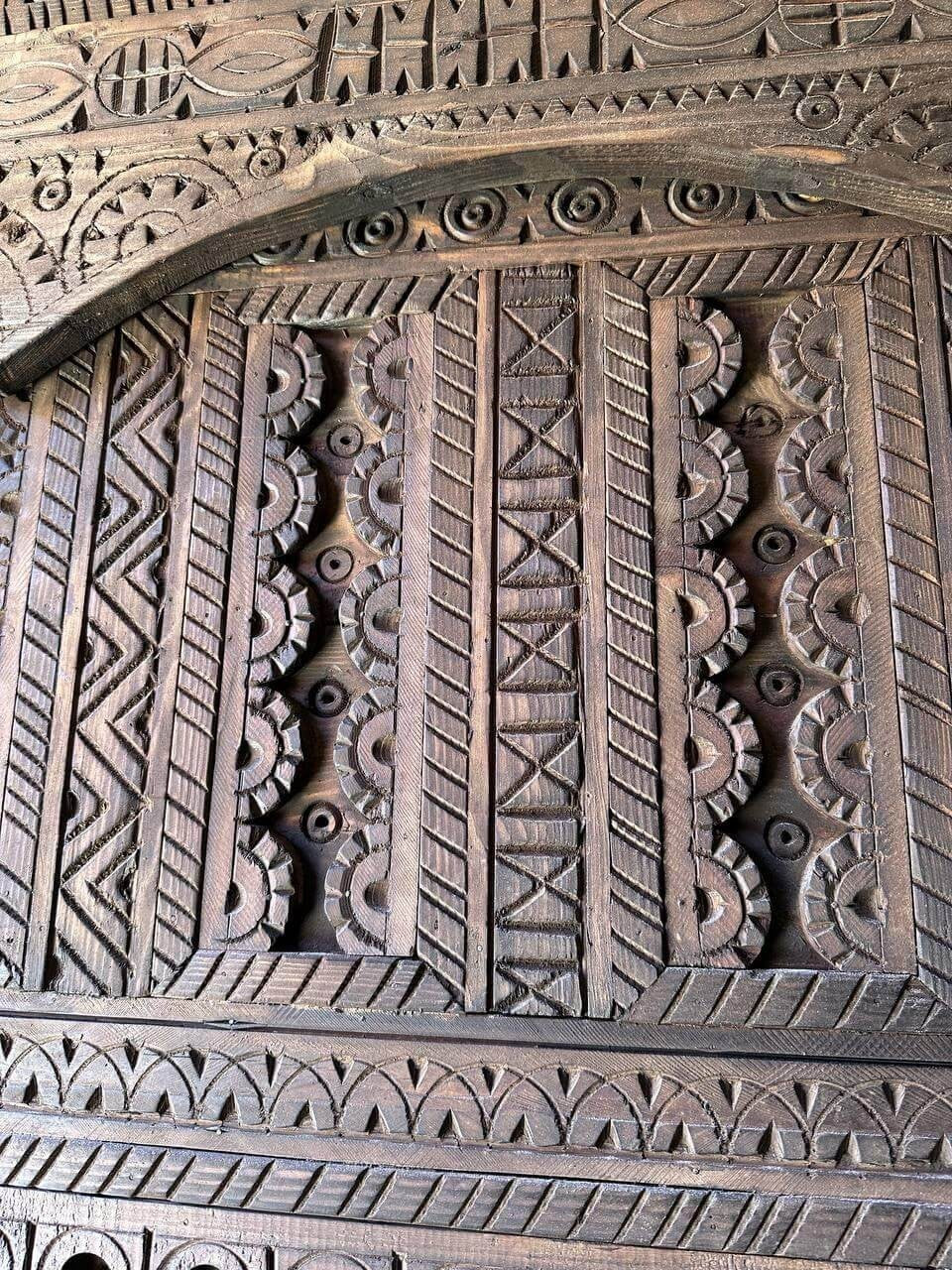 AtlasMuseCrafts dark wood door with intricate geometric Moroccan carvings. Handmade, natural wood, suitable for indoor/outdoor use.