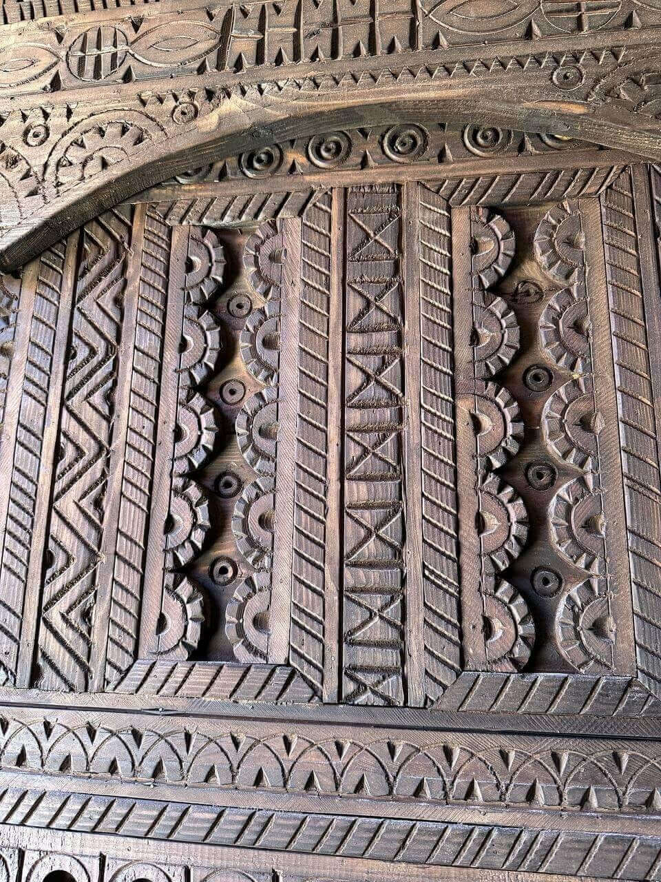 AtlasMuseCrafts dark wood door with intricate geometric Moroccan carvings. Handmade, natural wood, suitable for indoor/outdoor use.