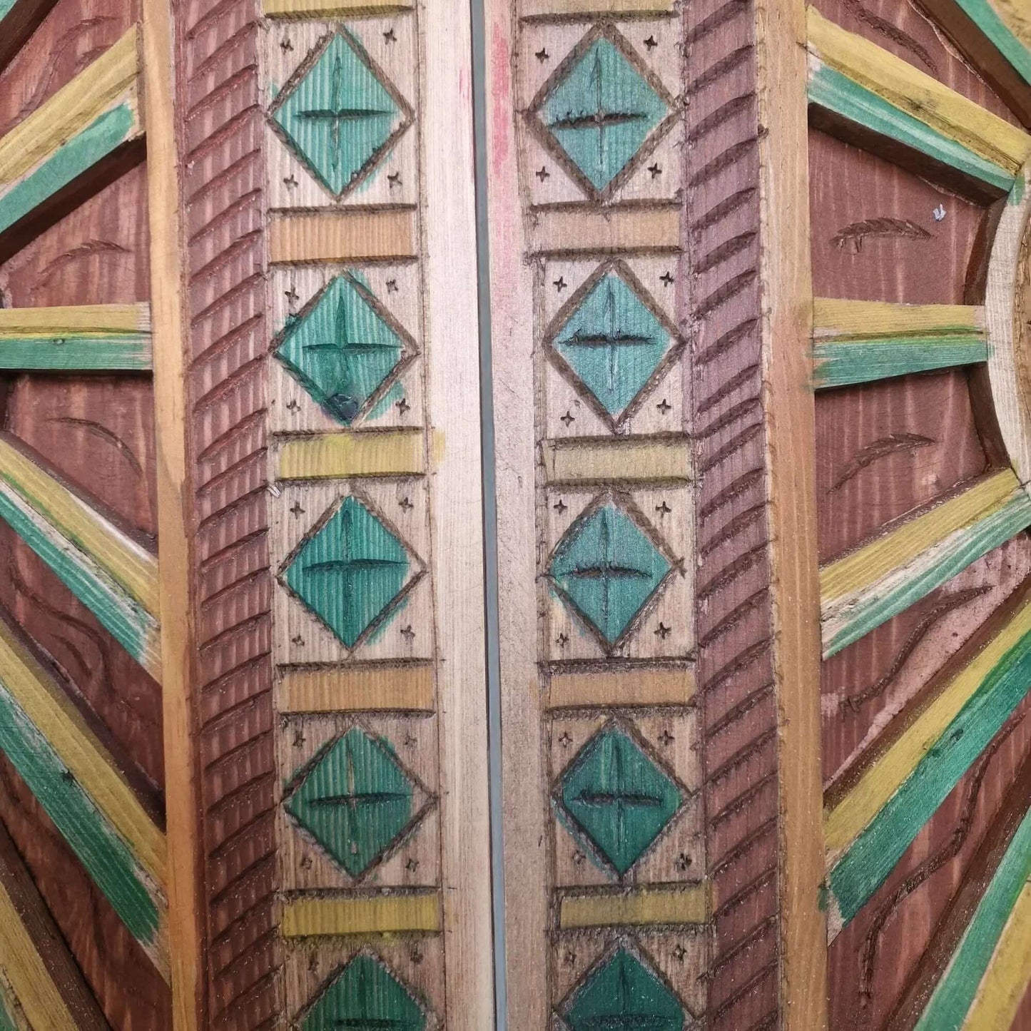 AtlasMuseCrafts hand-painted multicolor Moroccan wood door with geometric carving and green, yellow, and brown accents.