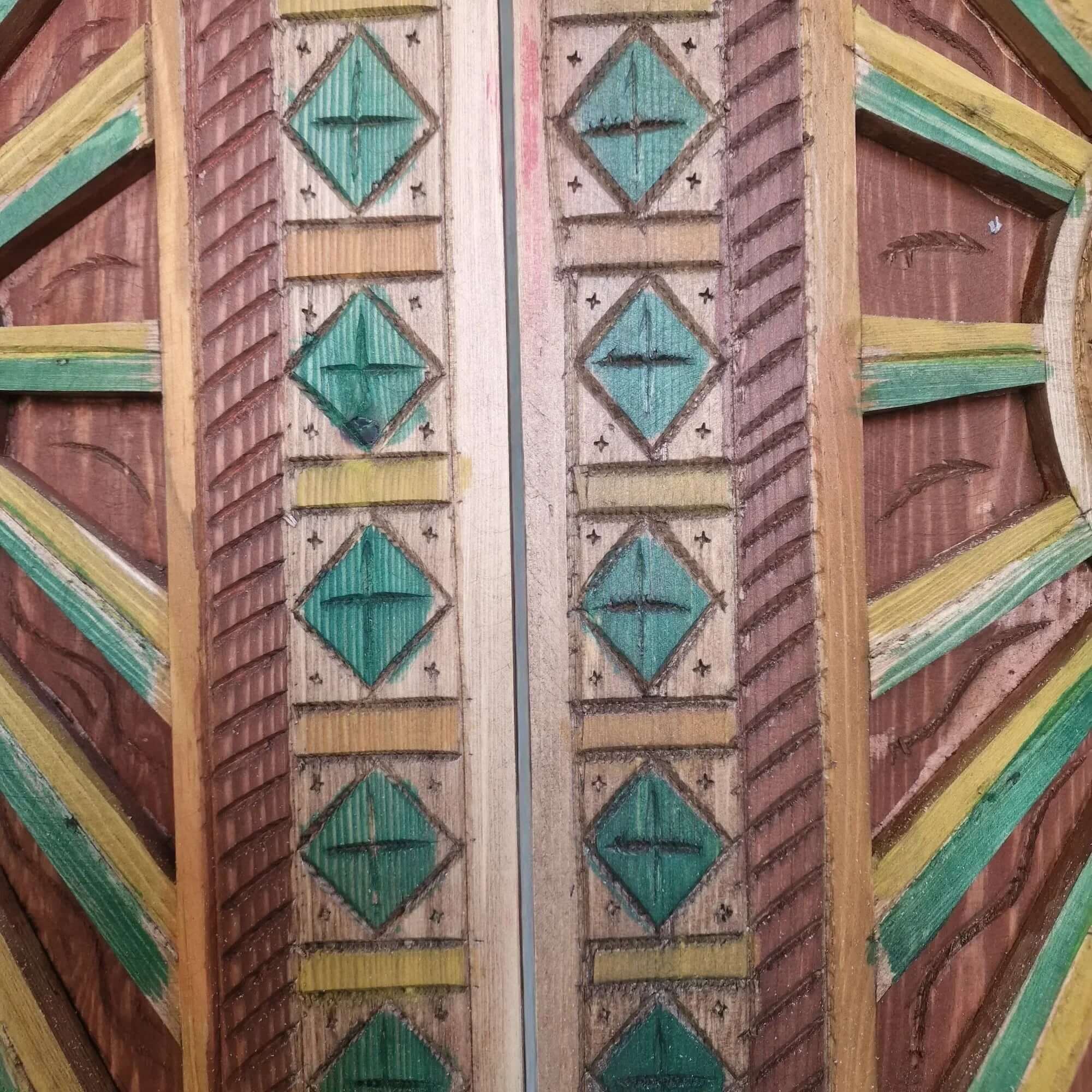 AtlasMuseCrafts hand-painted multicolor Moroccan wood door with geometric carving and green, yellow, and brown accents.