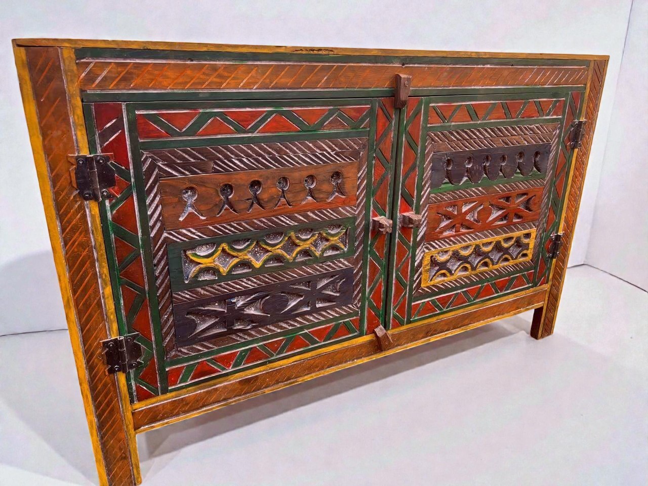 AtlasMuseCrafts handmade wooden cabinet with intricate Berber carvings in red, green, yellow, and brown. Rustic boho style storage.