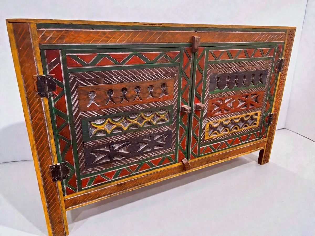 AtlasMuseCrafts handmade wooden cabinet with intricate Berber carvings in red, green, yellow, and brown. Rustic boho style storage.
