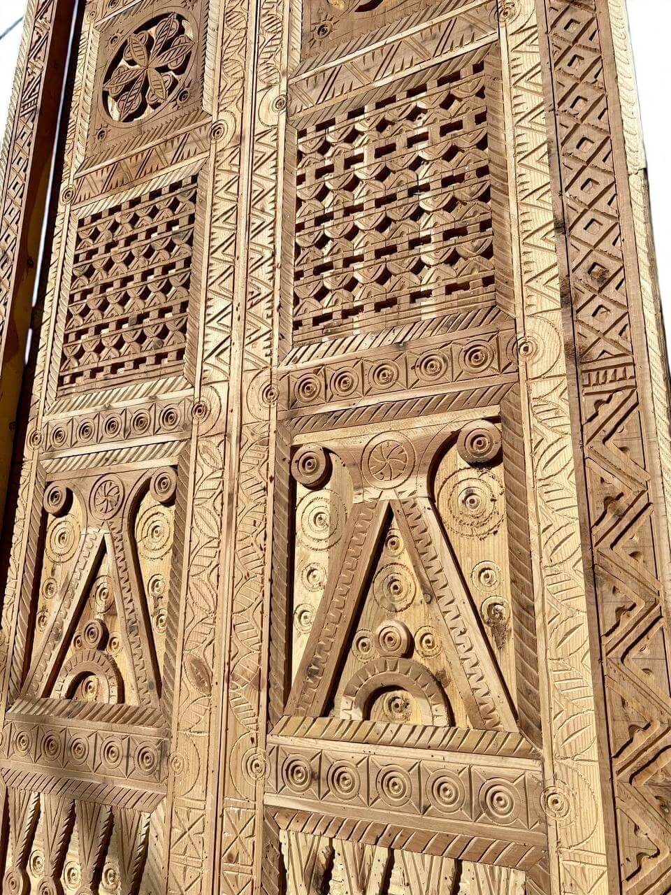 AtlasMuseCrafts antique double wooden door with intricate Moorish hand-carving and geometric patterns.