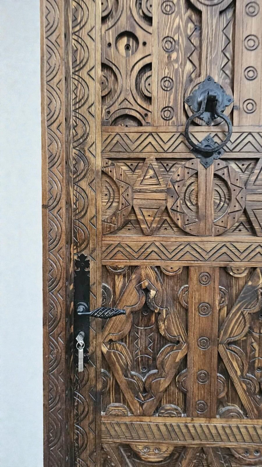 AtlasMuseCrafts antique Moroccan door made of natural wood with intricate Berber carving and black hardware.