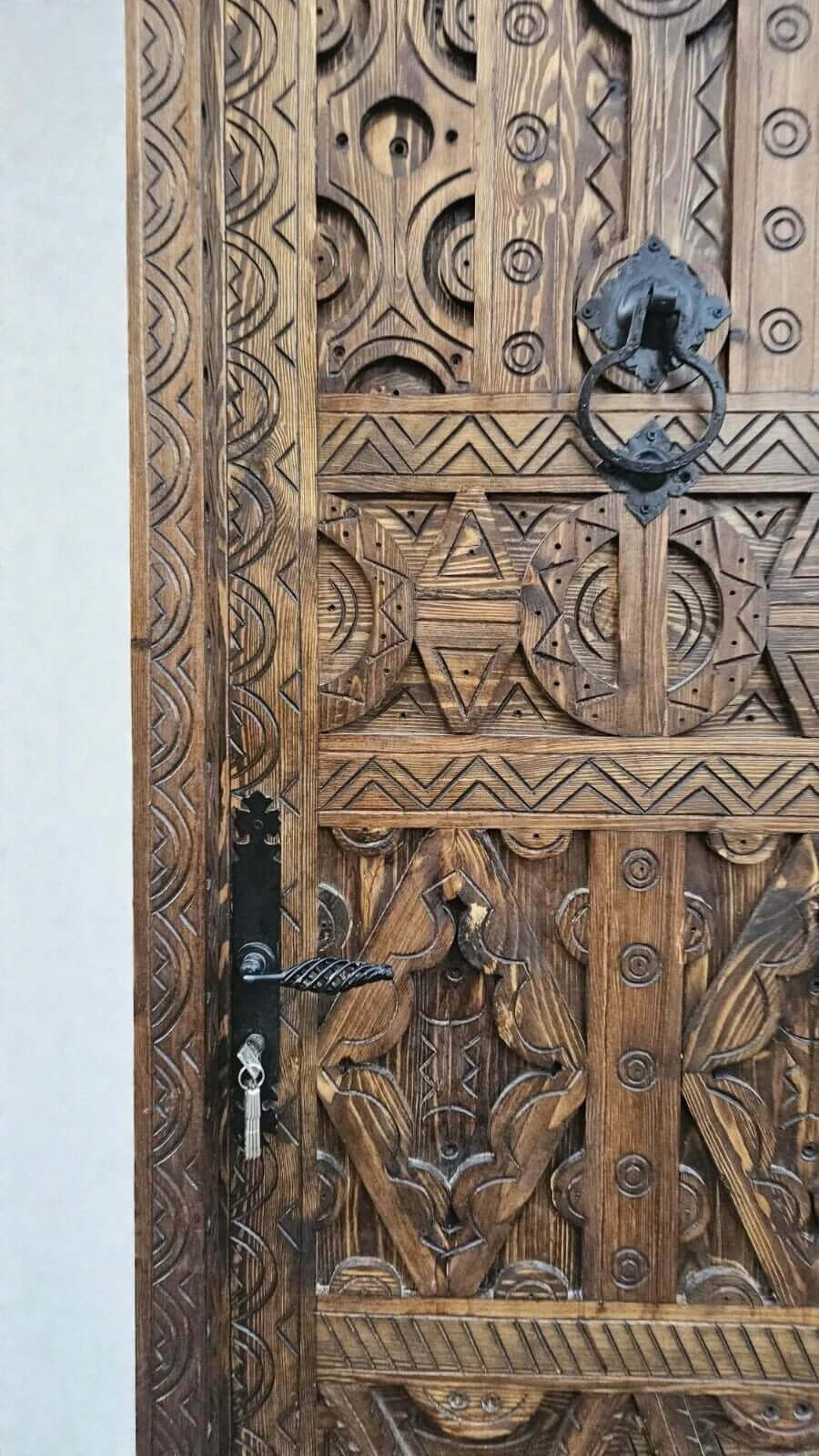 AtlasMuseCrafts antique Moroccan door made of natural wood with intricate Berber carving and black hardware.