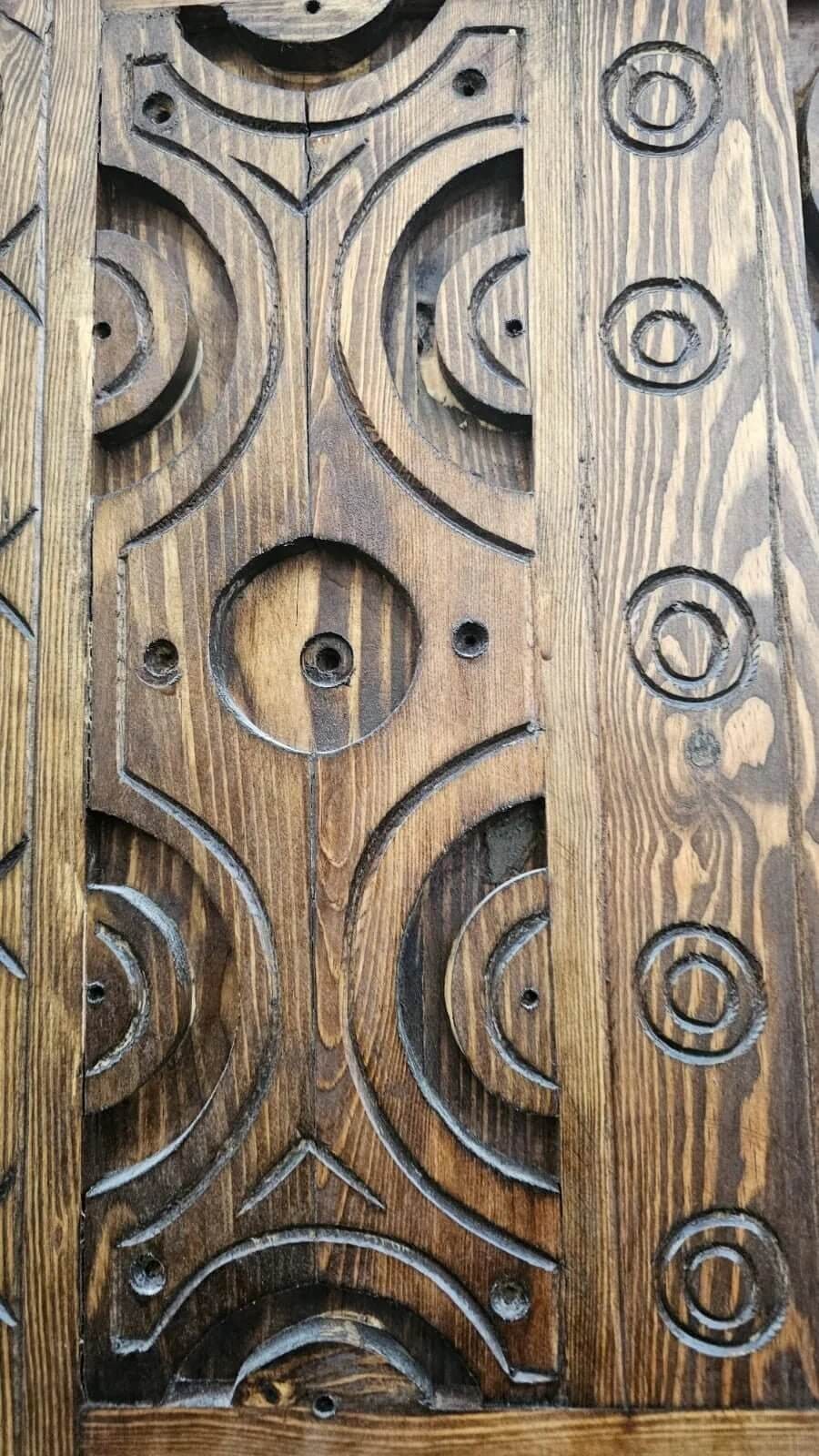 AtlasMuseCrafts antique Moroccan door, natural wood with intricate Berber carving, circular motifs and angular patterns.