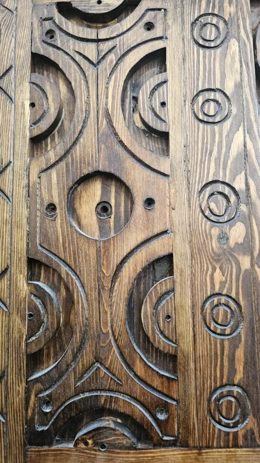 AtlasMuseCrafts antique Moroccan door, natural wood with intricate Berber carving, circular motifs and angular patterns.