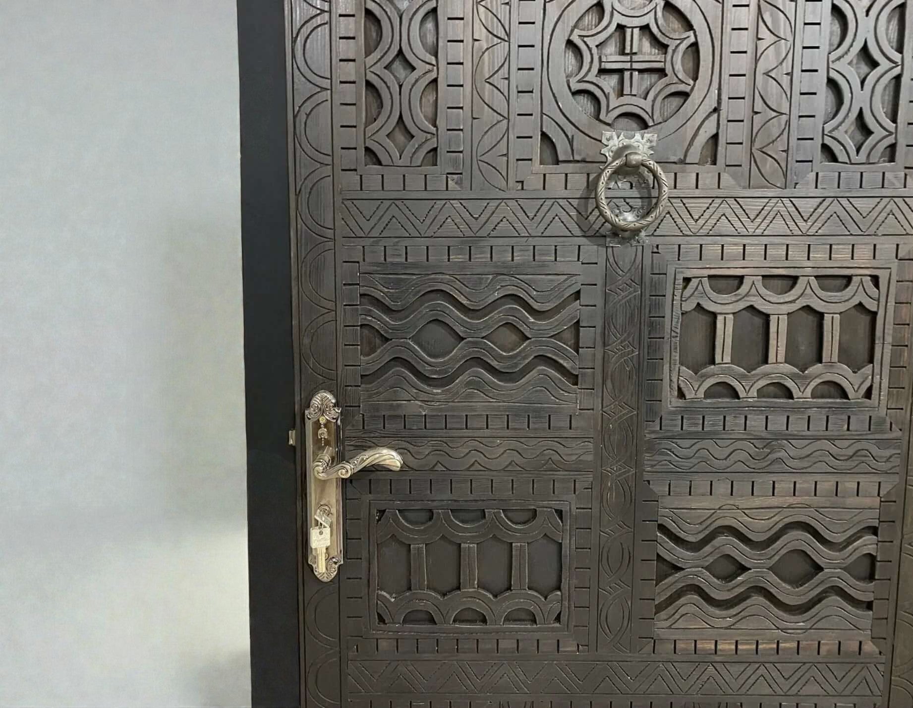 AtlasMuseCrafts dark wood door with intricate traditional floral carvings and metal hardware.