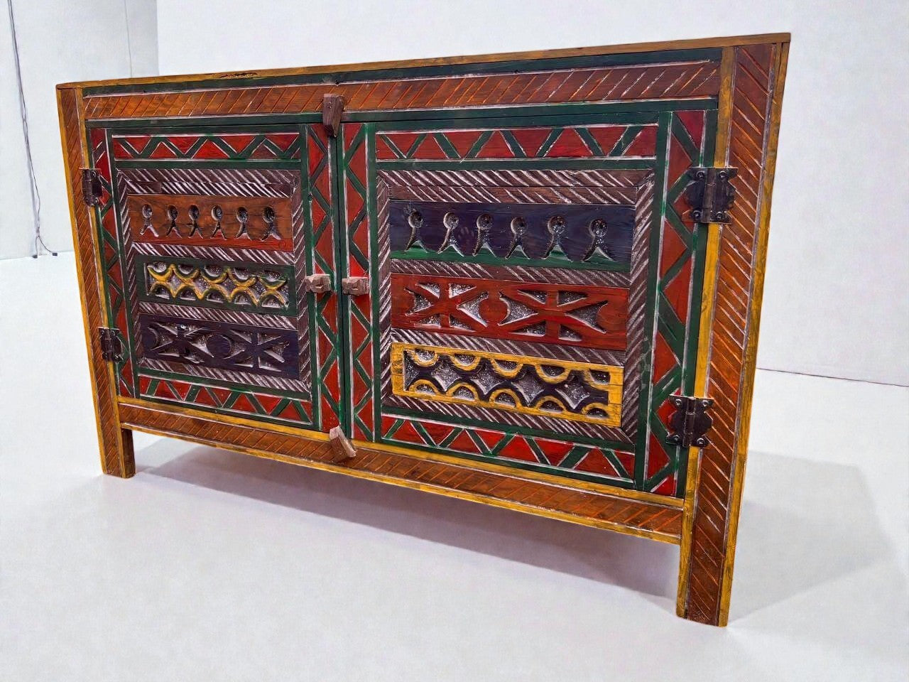 AtlasMuseCrafts handmade wooden cabinet with intricate Berber carvings in red, green, yellow, and blue. Features two doors and rustic boho style.