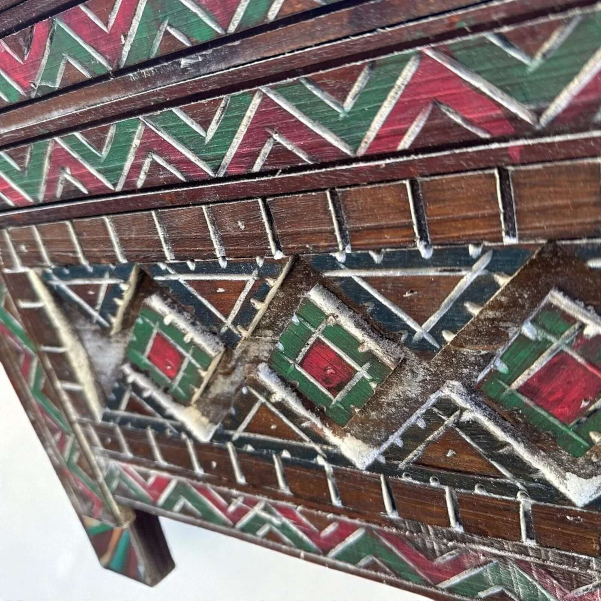 AtlasMuseCrafts handmade wooden cabinet with intricate red, green, and natural wood geometric carvings. Rustic boho style.