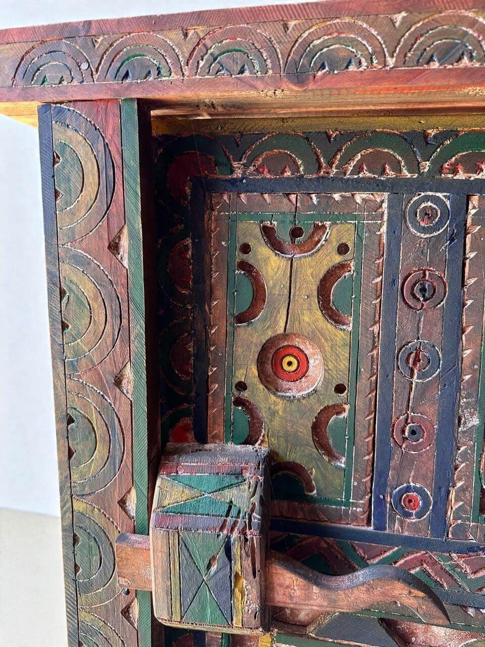 AtlasMuseCrafts handmade wooden door with brass knobs, featuring traditional Moroccan geometric carvings in red, green, yellow, and blue.
