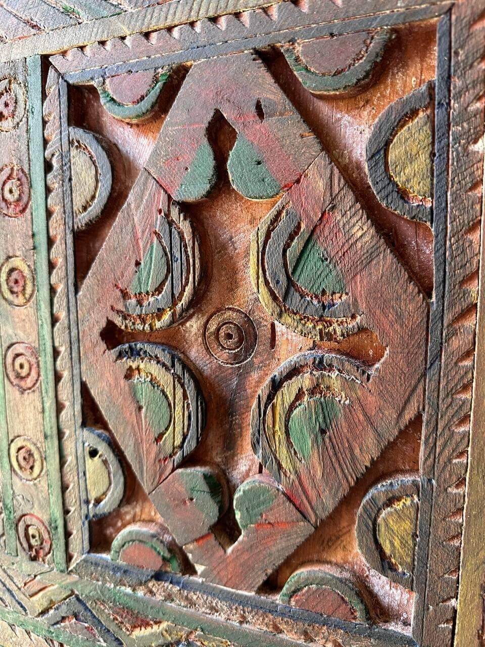 AtlasMuseCrafts handmade wooden door with brass knobs, featuring intricate Moroccan geometric carvings in natural wood with red, green, and yellow accents.