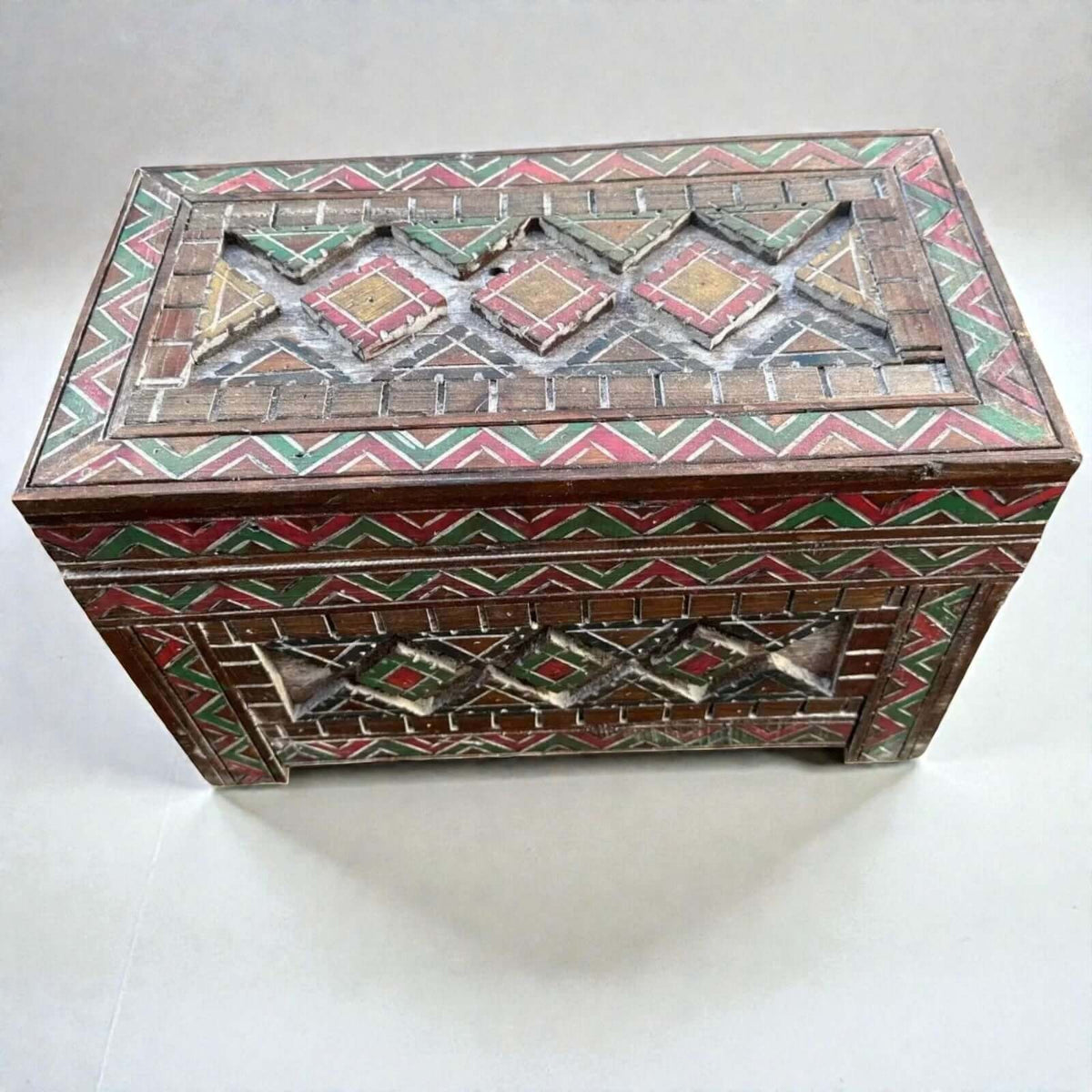 AtlasMuseCrafts handmade wooden storage cabinet with carved Berber patterns in red, green, and yellow.