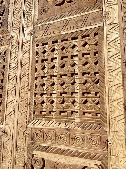 AtlasMuseCrafts antique Moroccan double door with intricate hand-carved geometric and arabesque patterns in natural wood.