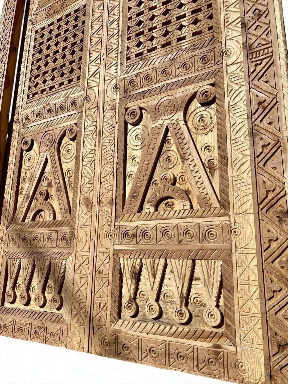 AtlasMuseCrafts antique Moroccan double door with intricate hand-carved geometric patterns in natural wood.