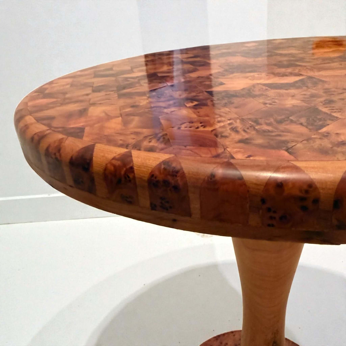 Round coffee table with solid wood marquetry top and curved pedestal