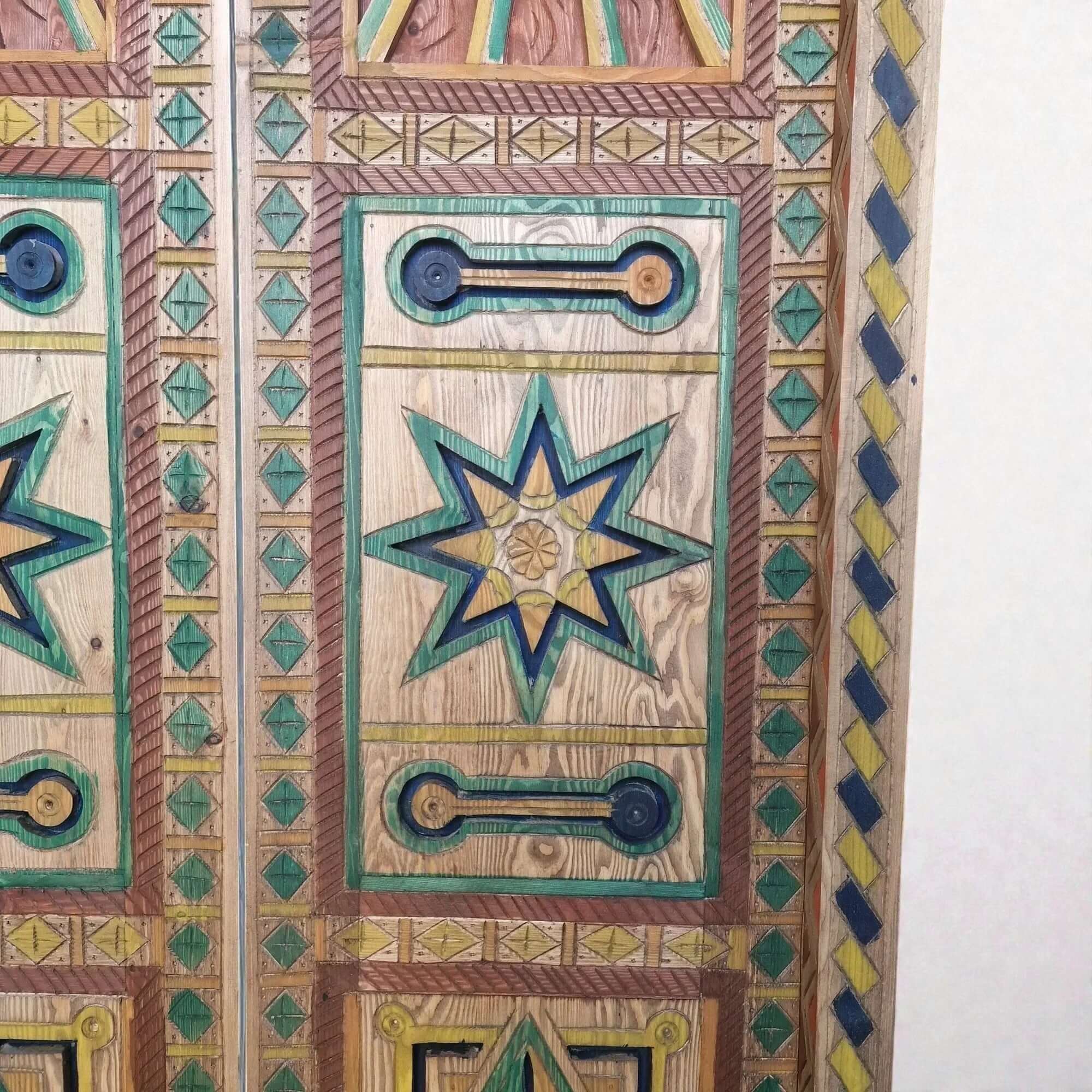 AtlasMuseCrafts hand-painted multicolor Moroccan door with geometric carving in wood, featuring star motifs and vibrant blue, green, and yellow accents.