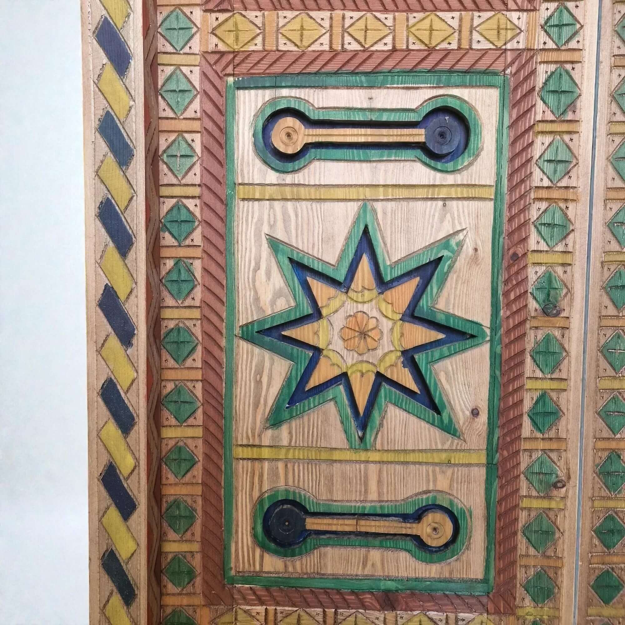AtlasMuseCrafts hand-painted multicolor Moroccan wood door with geometric carving and star motif.