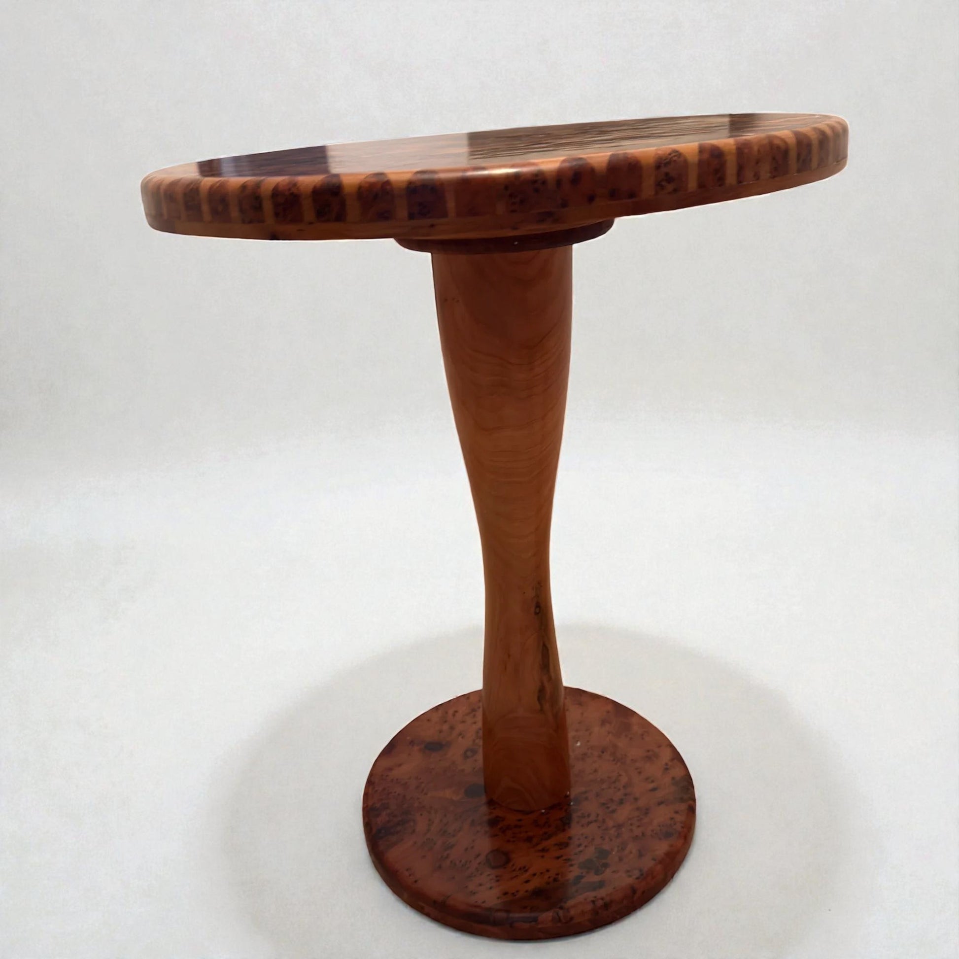 AtlasMuseCrafts handmade round solid wood coffee table with a tapered pedestal base and a natural wood finish.