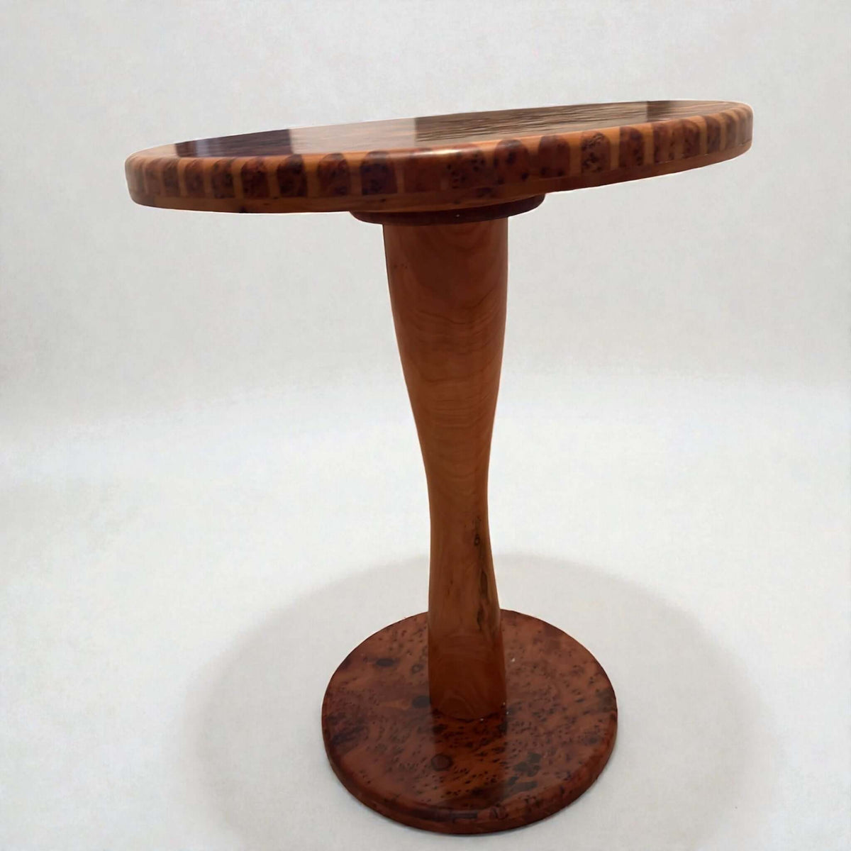 Round solid wood coffee table with tapered pedestal and natural finish