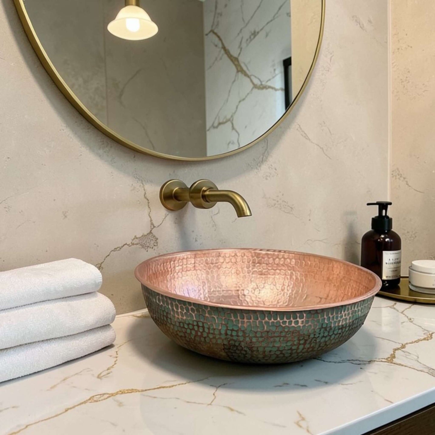 Green Patina Brass Vessel Sink displayed on a marble countertop with towels and accessories.