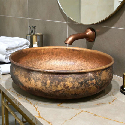 Hammered Copper Bathroom Sink displayed on a marble countertop next to a modern faucet and towels.
