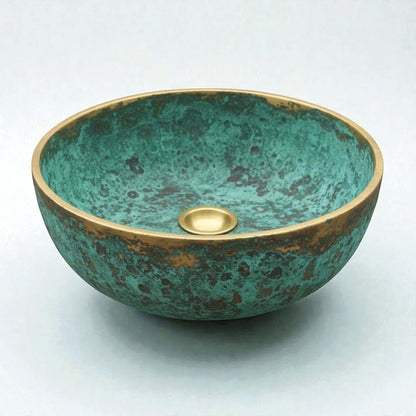 Decorative copper sink with a green and gold finish on a white background