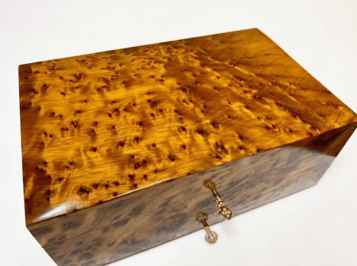 Brass key beside large lockable wooden jewelry box