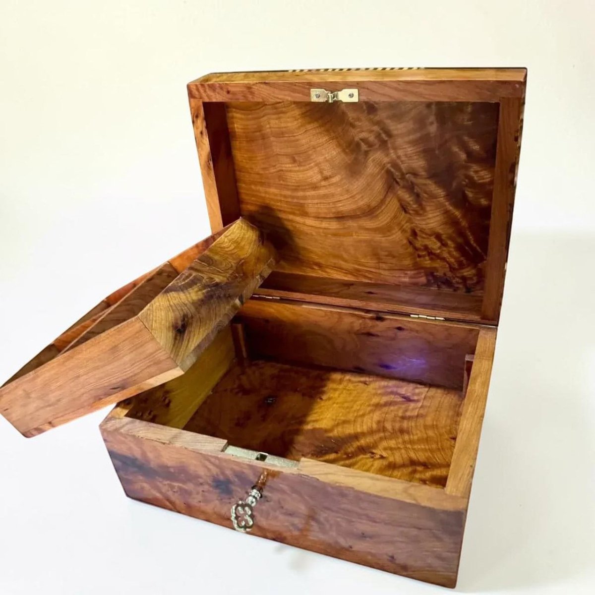 AtlasMuseCrafts handcrafted Thuya wood keepsake box with swirling grain patterns and a lockable lid with a decorative brass key.